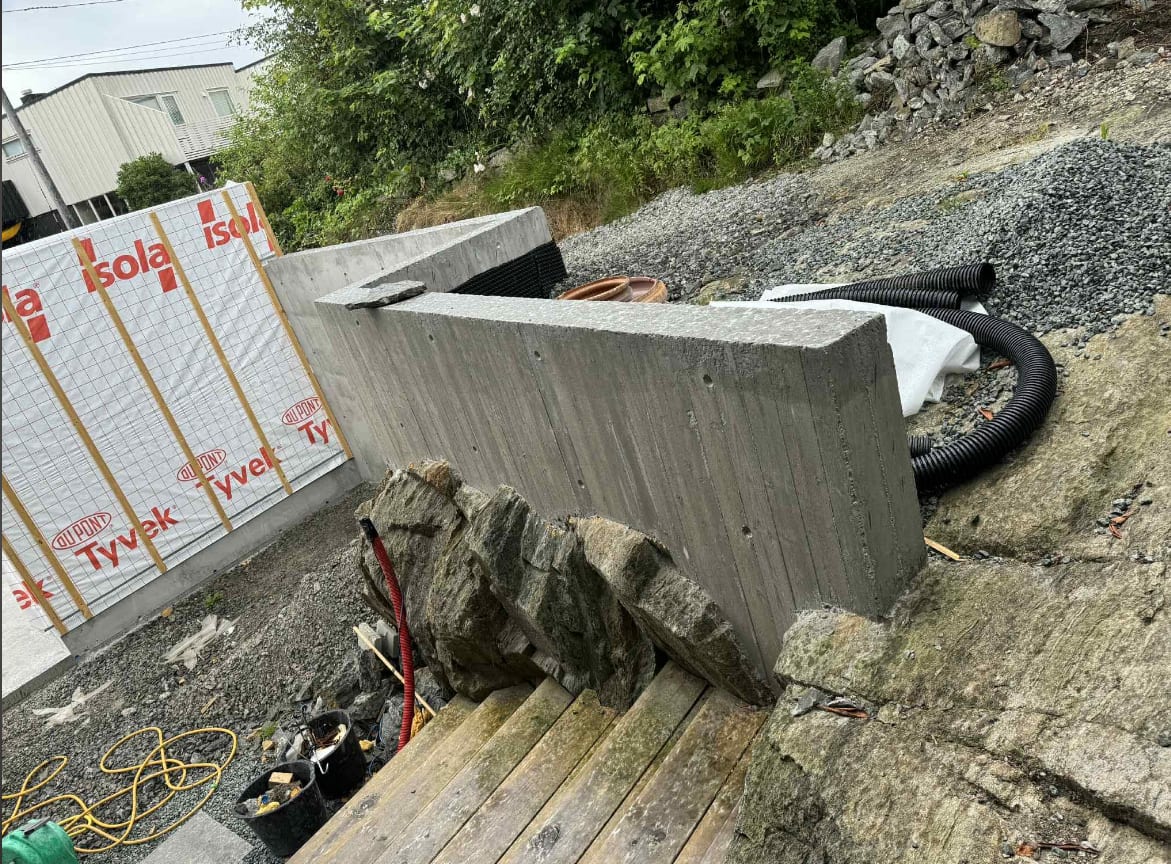 Plasstøpt støttemur med natursteinsfront under bygging